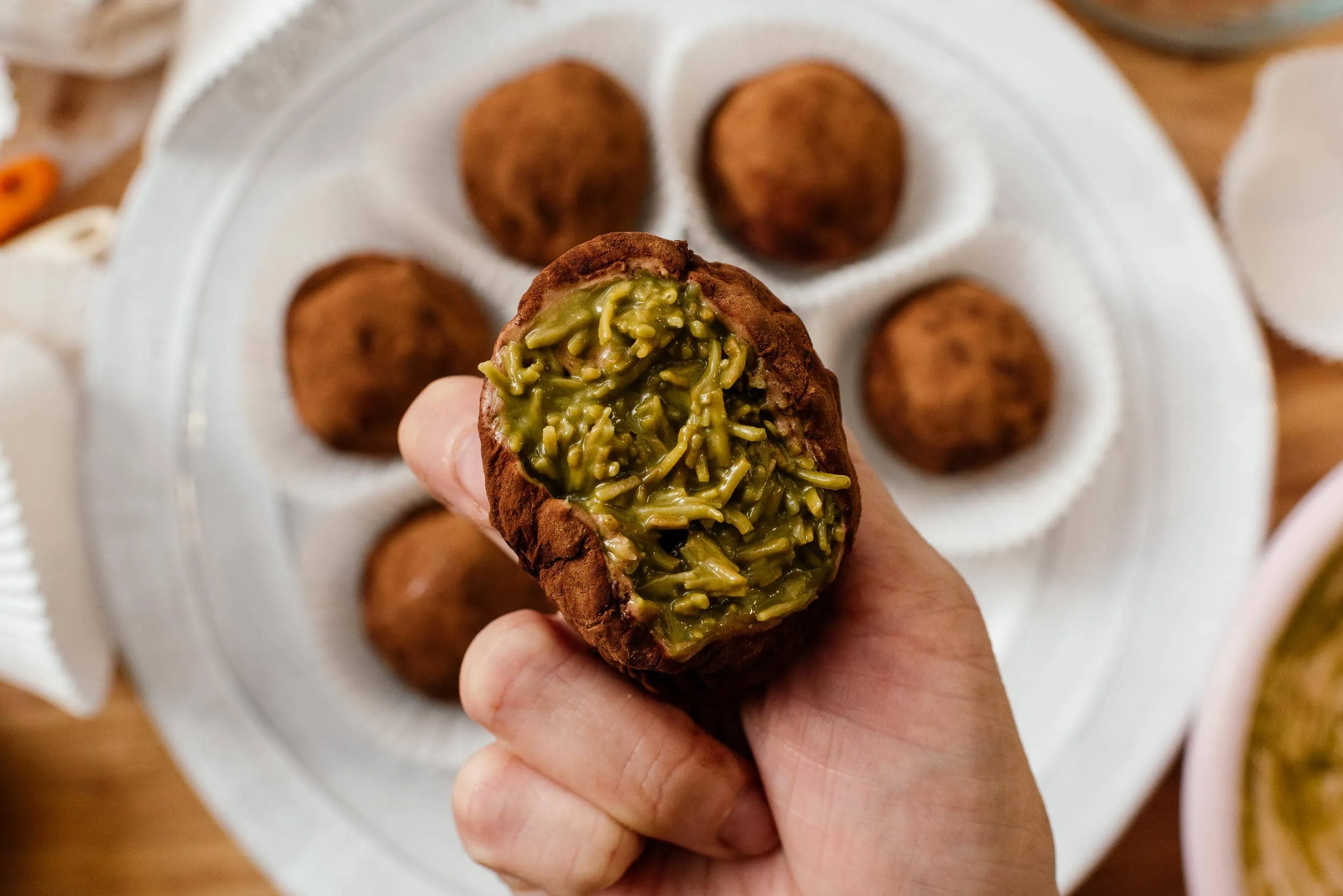 Hand holding a dubai chocolate cookie with pistachio cream filling